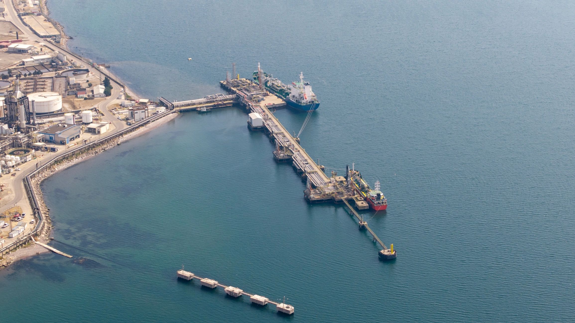 Aerial view of cargo ships docking at an industrial oil refinery port